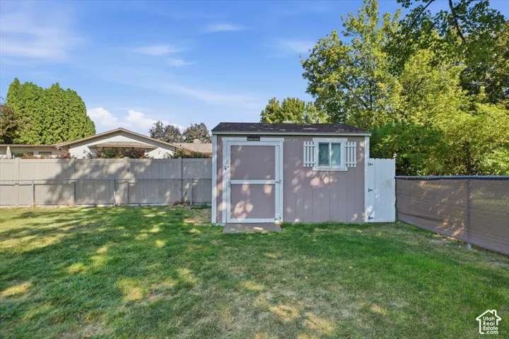 Backyard featuring a storage shed with a window and white shutters, and a privacy fence