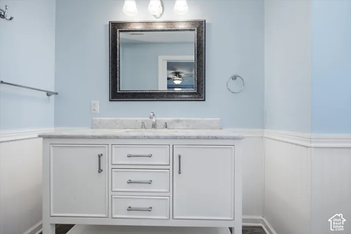 White vanity with multiple drawers and cabinet storage, under-mount sink, chrome faucet, and a decorative framed mirror
