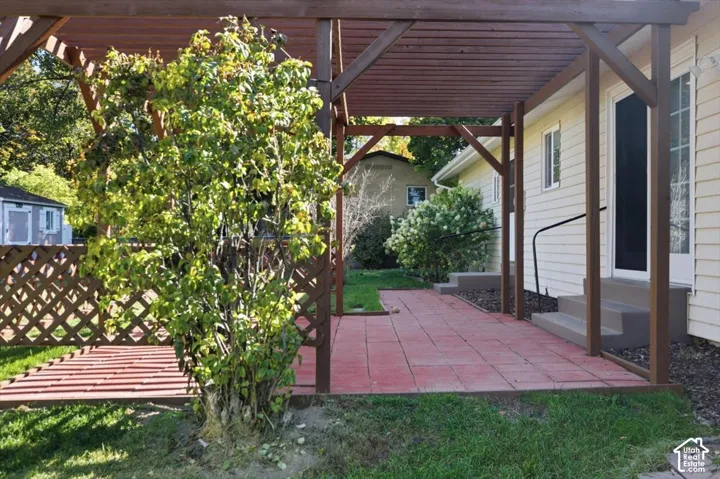Pergola structure with a lattice side panel and red paver patio