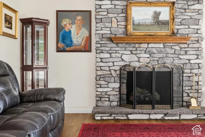 Stone-clad fireplace with a wood mantle, hearth, and fire screen