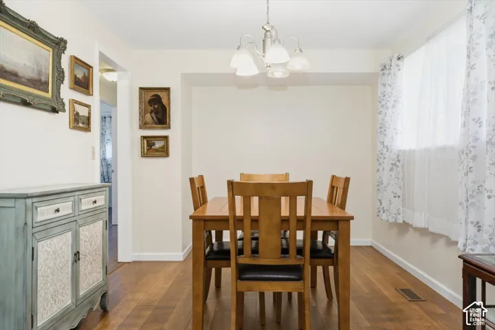 Wood-finish flooring with a multi-light chandelier and a window with sheer and patterned curtains