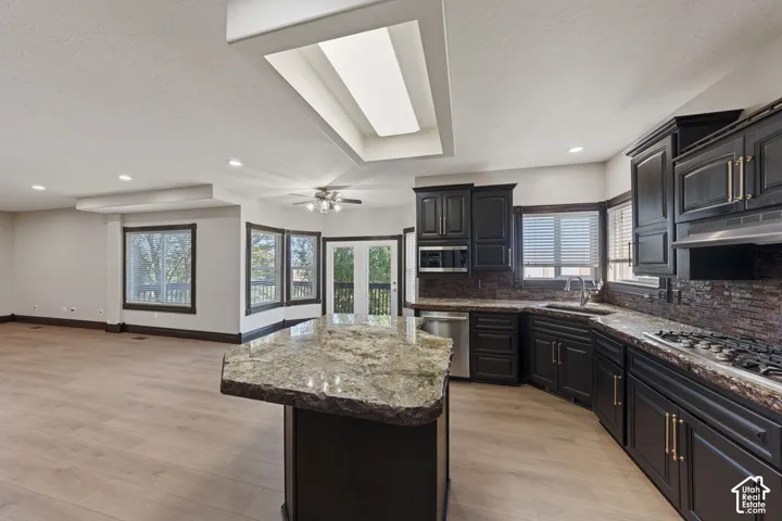Kitchen with dark cabinetry, integrated stainless steel appliances, and a gas cooktop