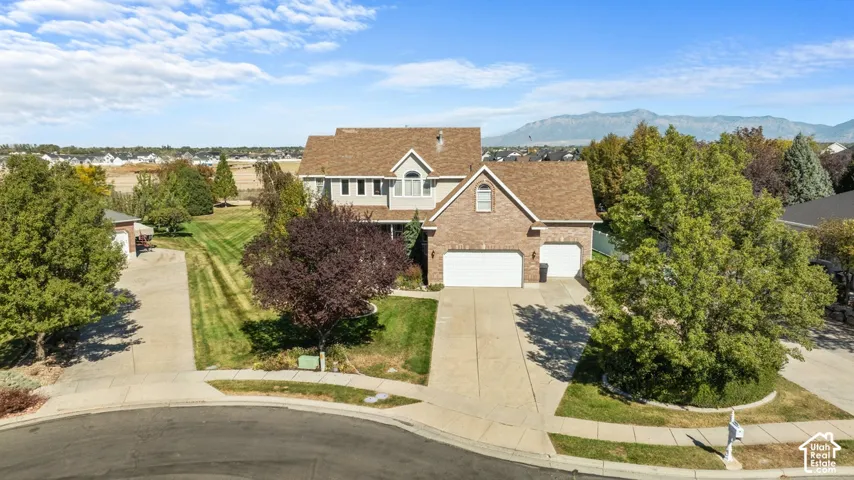 Brick and siding exterior, multi-car garage, mature landscaping, and an expansive lawn