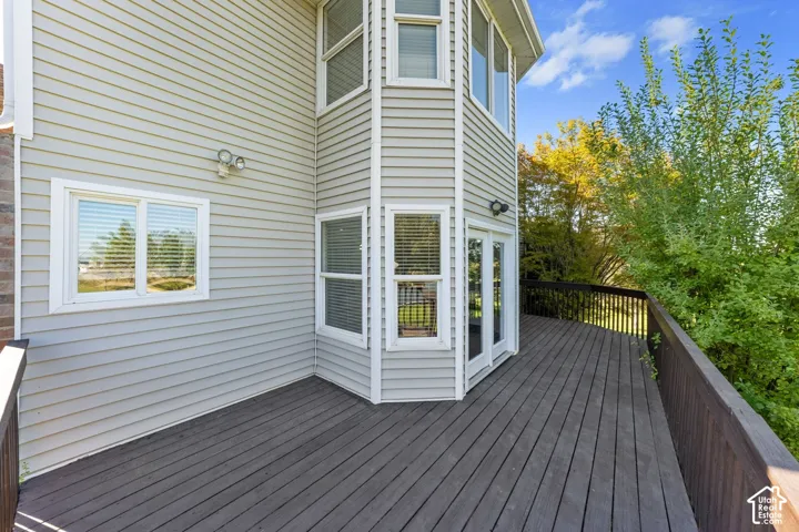 Expansive wood-finish deck with dark railing, multiple windows, and exterior siding