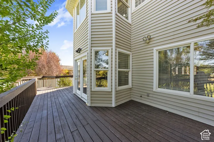 Expansive wood deck with full railing, providing outdoor access through double French doors and featuring an octagonal architectural element with large windows