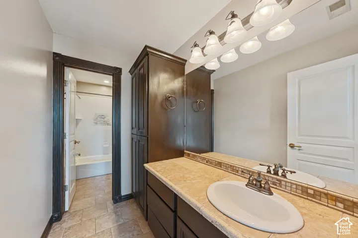 Vanity with a solid surface countertop, integrated sink, and an extensive mirror