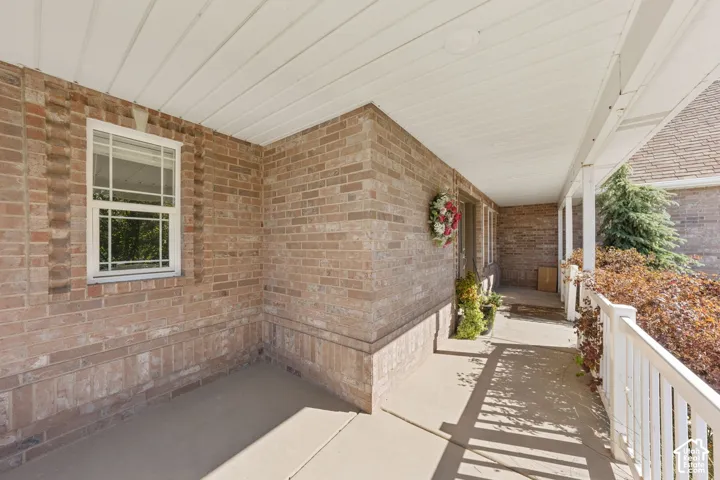Covered front porch featuring brick exterior, white window frames, and white railing