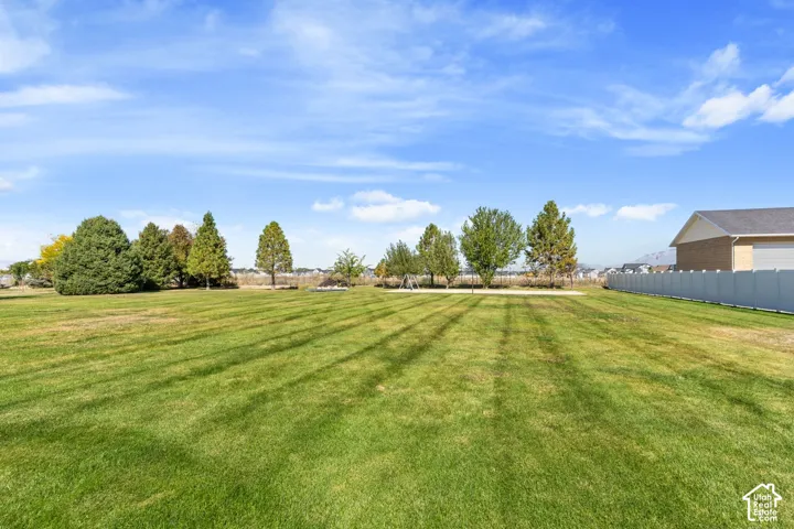 Expansive green lawn with mature trees and a privacy fence