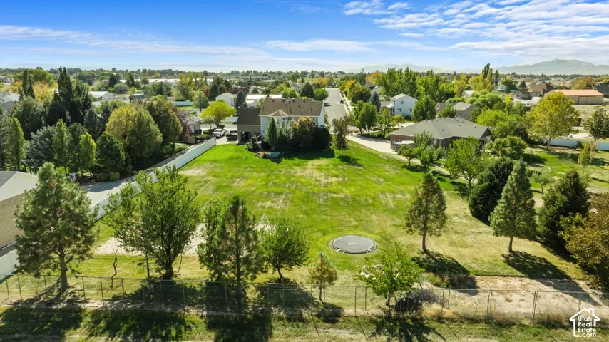 Expansive lot featuring a large grassy area, mature trees, and partial fencing