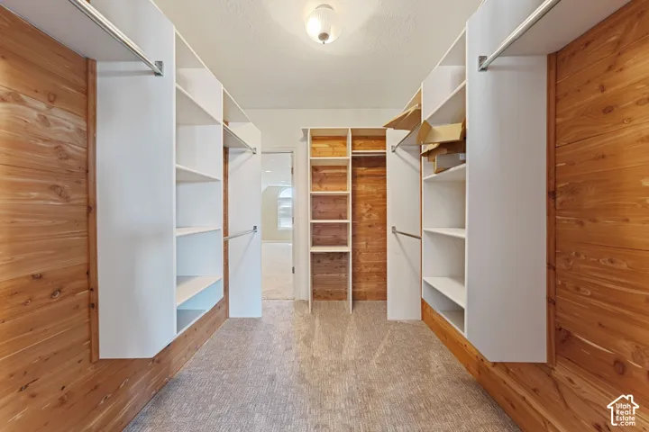 Walk-in closet with extensive built-in shelving, hanging rods, and wood paneling