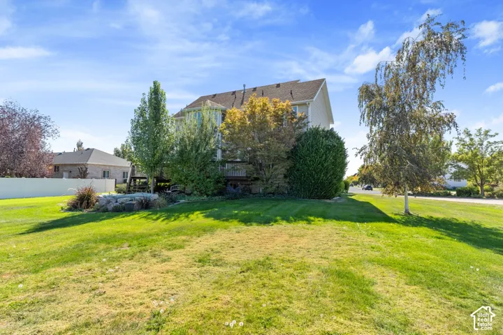 Expansive landscaped property featuring a multi-level deck, mature trees, and a decorative rock garden