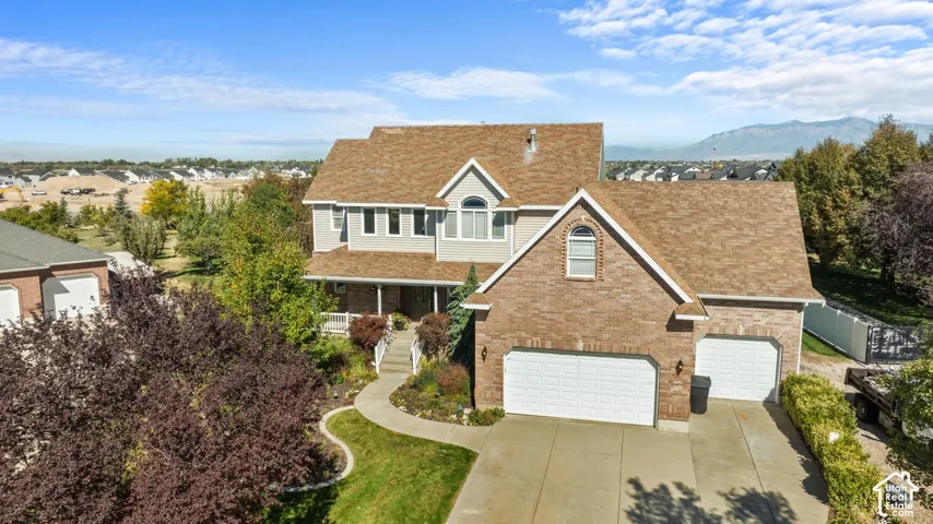 Brick and siding exterior with a multi-level roofline, featuring an attached two-car garage, mature landscaping, and an inviting front porch