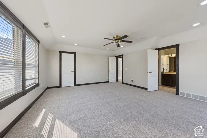 Spacious room featuring light gray carpet, multiple windows with blinds, and recessed lighting