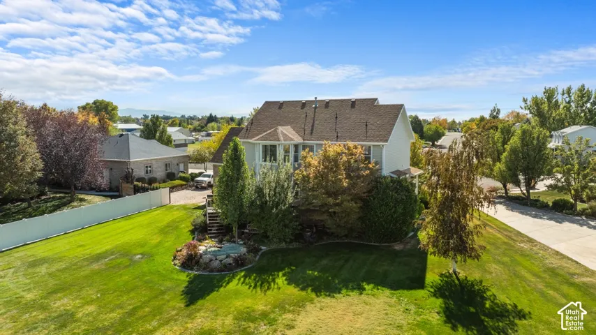 Expansive green lawn, mature trees, and a multi-level deck with steps