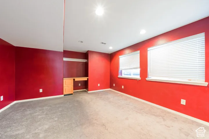 Built-in desk with wood-finish cabinetry, two windows with blinds, and recessed lighting
