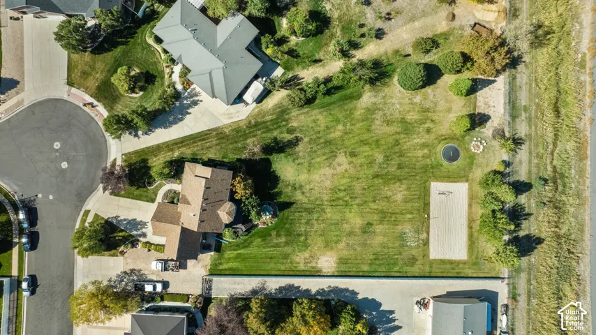 Expansive property with a large, landscaped lawn, a sand court, and a circular drive