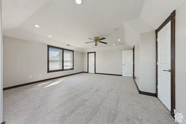 Spacious room with carpeting, recessed lighting, ceiling fan, and multiple paneled doors
