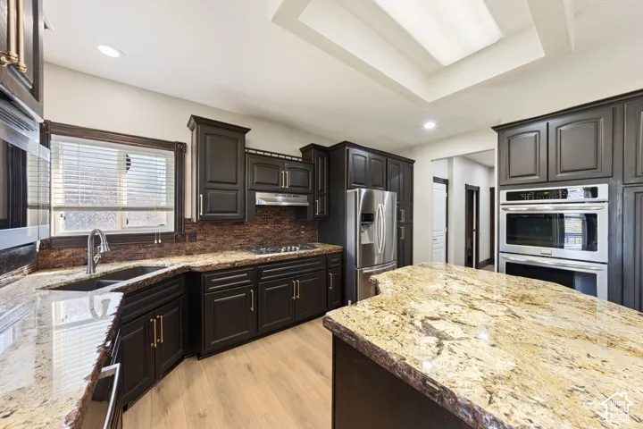 Dark wood cabinetry with stone countertops, stainless steel appliances, and wood-finish flooring
