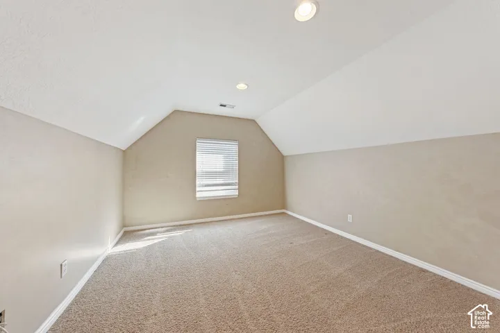 Recessed lighting, sloped ceilings, textured walls, window with blinds, and carpeted flooring