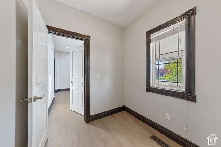 Light wood-finish flooring, dark wood-finish trim, white interior doors, and a window with blinds