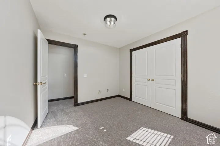 Light gray wall paint, dark wood-finish trim, white paneled doors, carpet flooring, and a flush mount ceiling light fixture