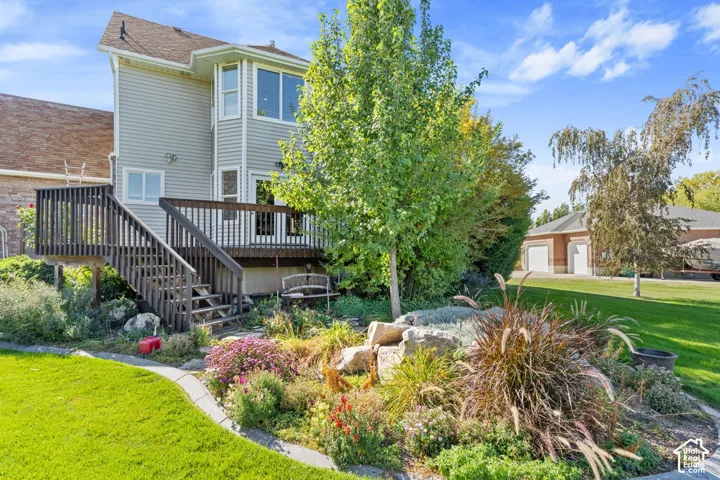 Multi-level deck with dark wood railing and stairs, mature trees, and a decorative rock garden