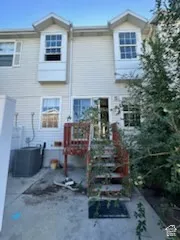 Rear exterior featuring siding, bay windows, and a wood deck with stairs leading to a concrete patio