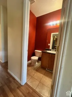 Powder room featuring a single vanity with wood-finish cabinetry, a white basin, a mounted mirror, and tile flooring
