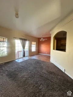 Expansive room featuring carpet flooring, multiple windows, and a sliding glass door