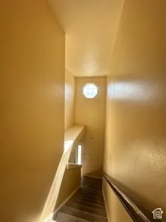 Carpeted staircase with a metal handrail and an octagonal window