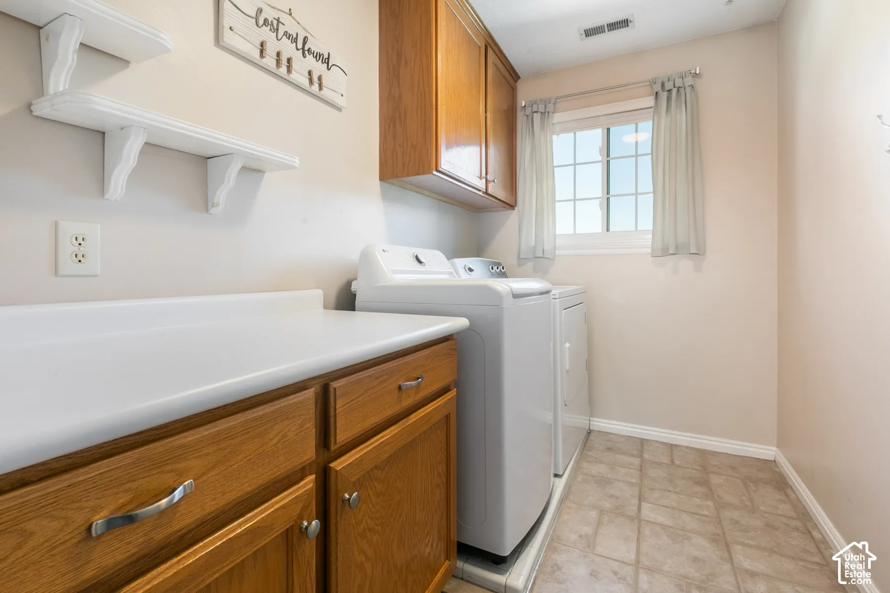 Wood-finish cabinetry with silver-tone hardware, white countertop, and tile flooring