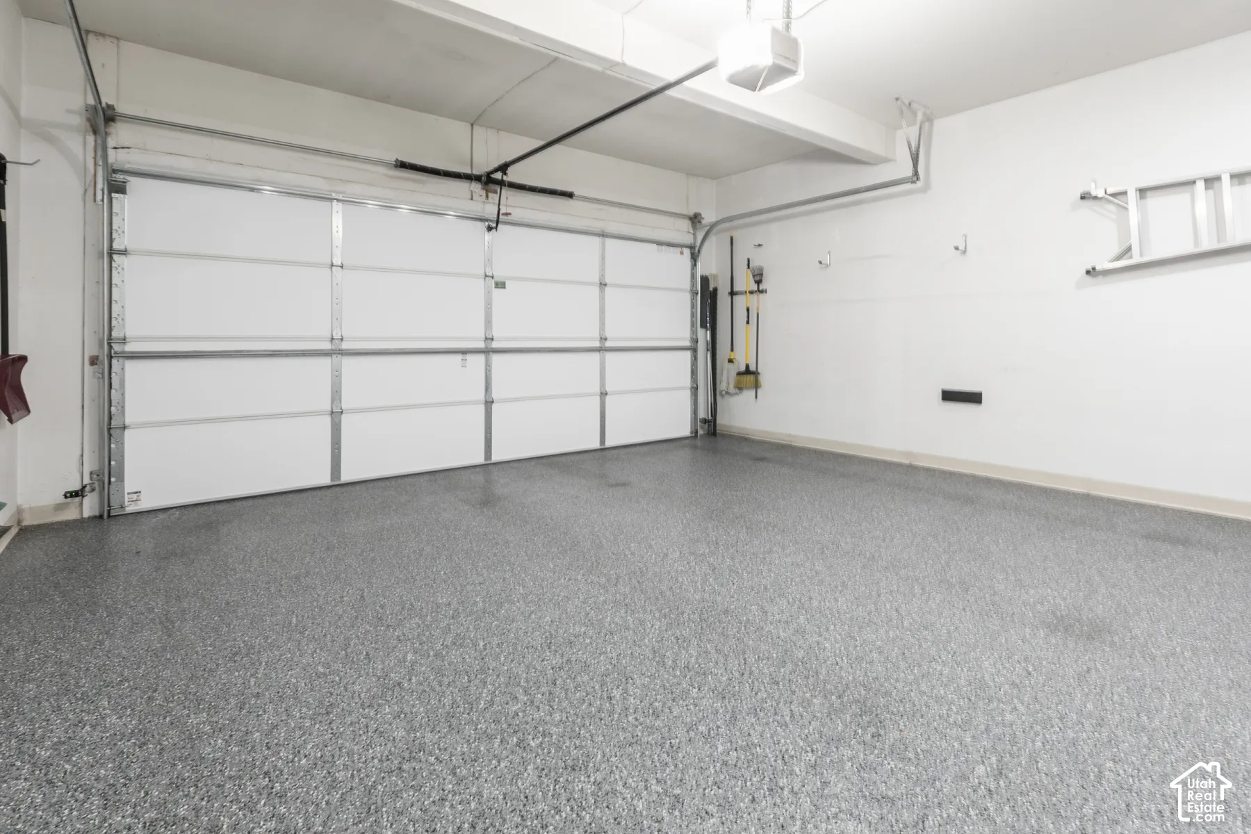 Garage space featuring an automatic overhead door, a light fixture, and a durable epoxy floor finish