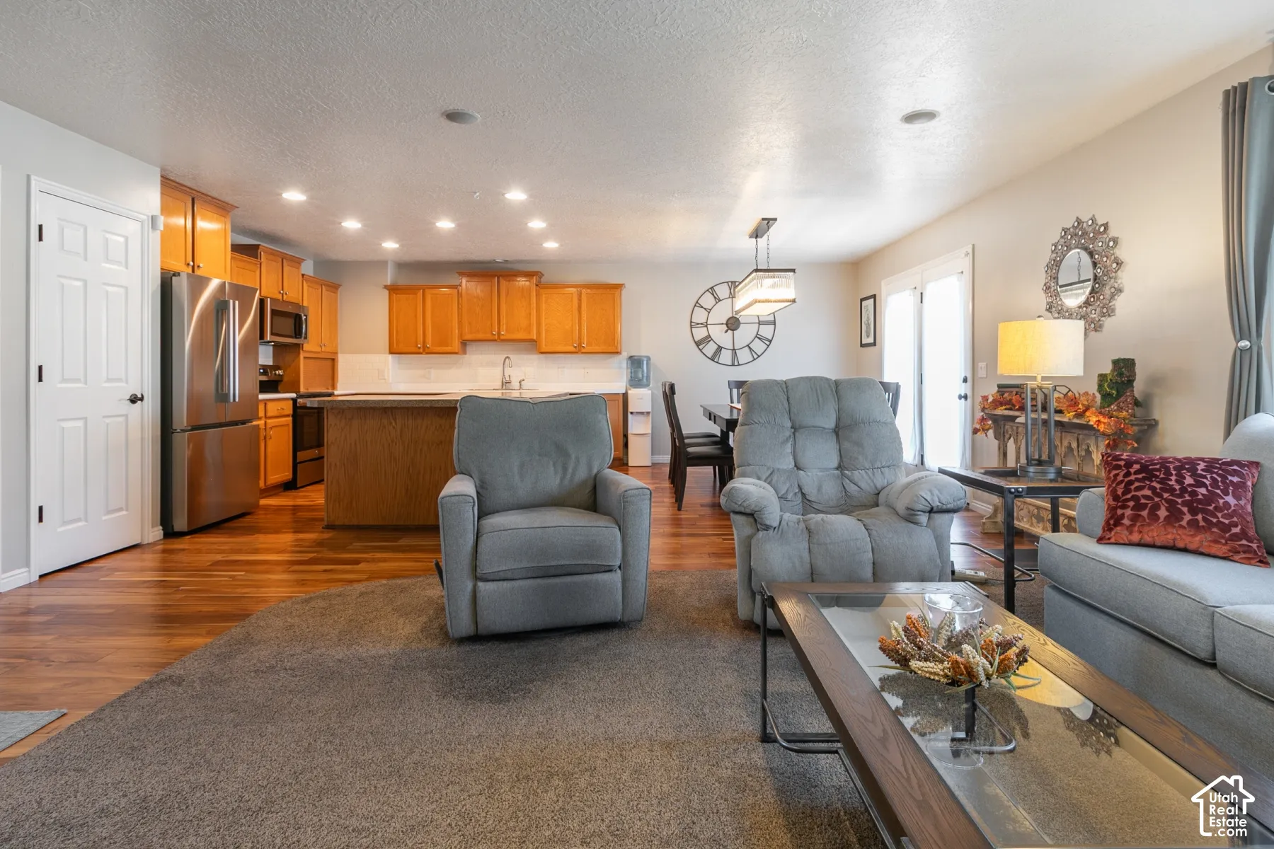 Open concept living area with wood-finish flooring, stainless steel appliances, recessed lighting, and a kitchen island