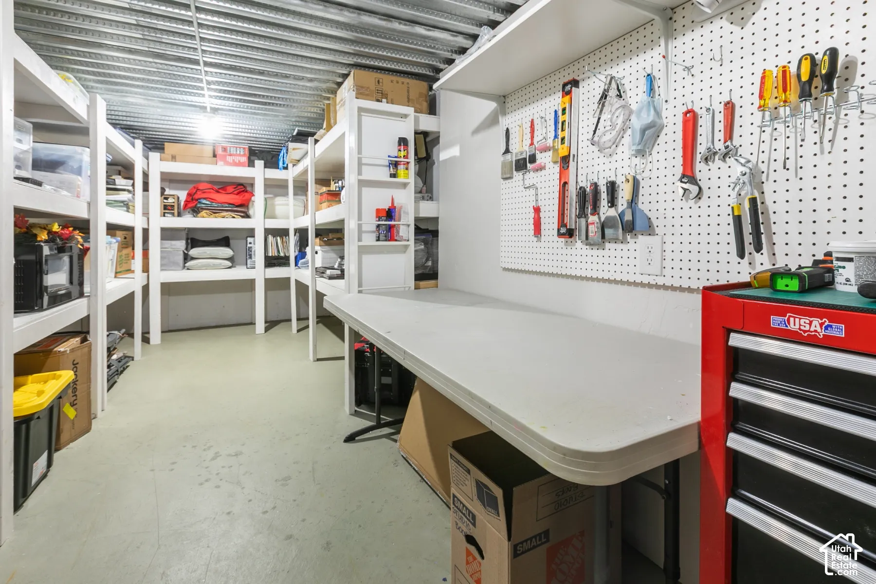 Dedicated workspace featuring a built-in workbench, pegboard organization system, and overhead lighting