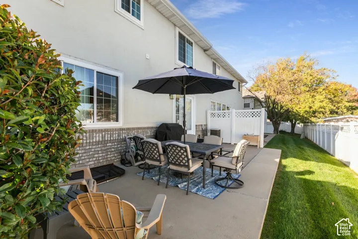Concrete patio, white privacy fencing, manicured lawn, and mature foliage
