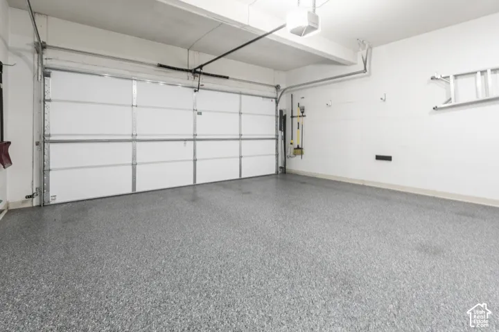 Garage space featuring an automatic overhead door, a light fixture, and a durable epoxy floor finish