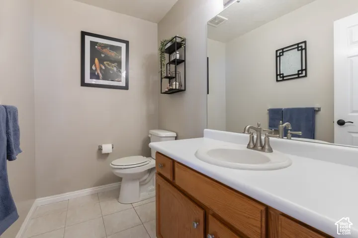 Vanity with integrated sink, brushed nickel faucet, wood-finish cabinetry, and tiled flooring