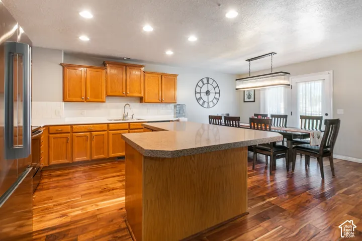 Kitchen featuring wood cabinetry, white subway tile backsplash, stainless steel appliances, and a central island with a countertop