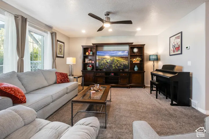 Recessed lighting, ceiling fan, carpeted flooring, and a built-in media console