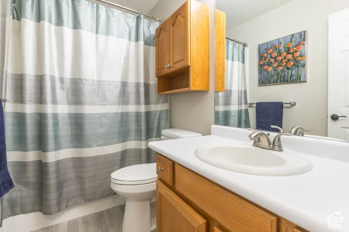 Bathroom featuring a white sink basin, brushed nickel faucet, wood-finish cabinetry, and light wood-finish flooring