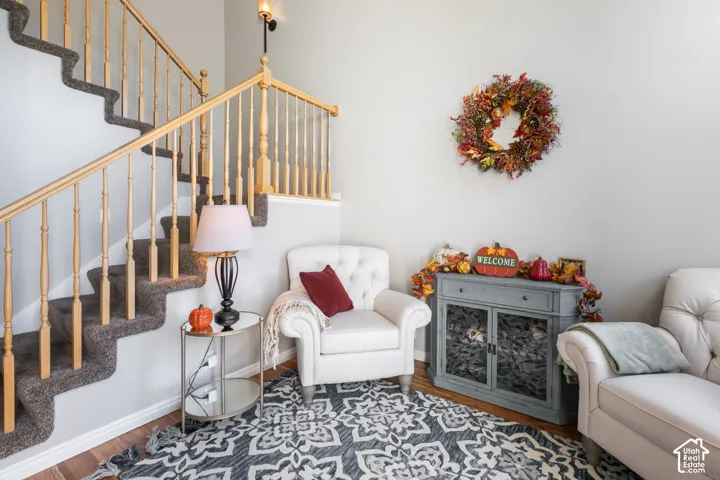 Staircase with wood balusters and carpeted treads, wood-finish flooring, and a wall-mounted light fixture