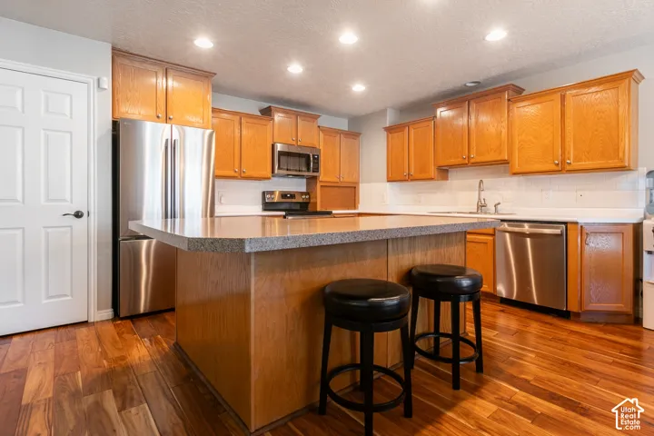 Hardwood flooring with a kitchen island featuring a stone countertop