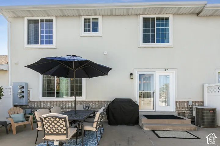 Rear patio with concrete surface, white vinyl privacy fence, and dual pane windows
