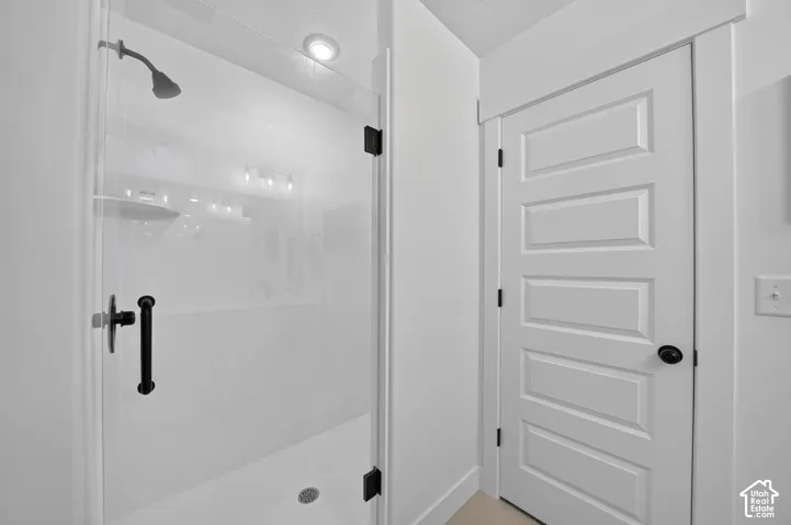 Walk-in shower with clear glass enclosure and matte black hardware, featuring a recessed ceiling light