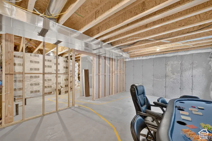 Unfinished basement featuring exposed joists, ductwork, wood framing, and concrete walls