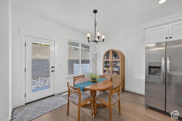 White shaker-style cabinetry, stainless steel refrigerator, and wood-finish flooring