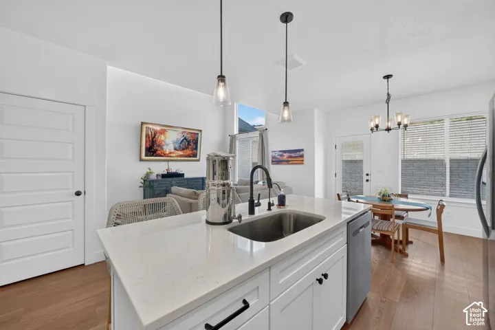 Kitchen island with a built-in sink, stainless steel dishwasher, and two pendant lights