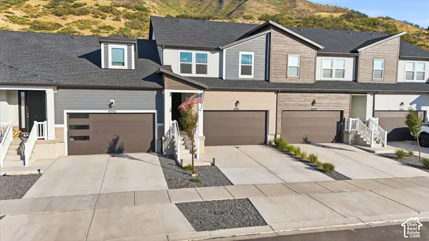 Townhome exterior featuring varied siding materials, attached garages, and a paved driveway