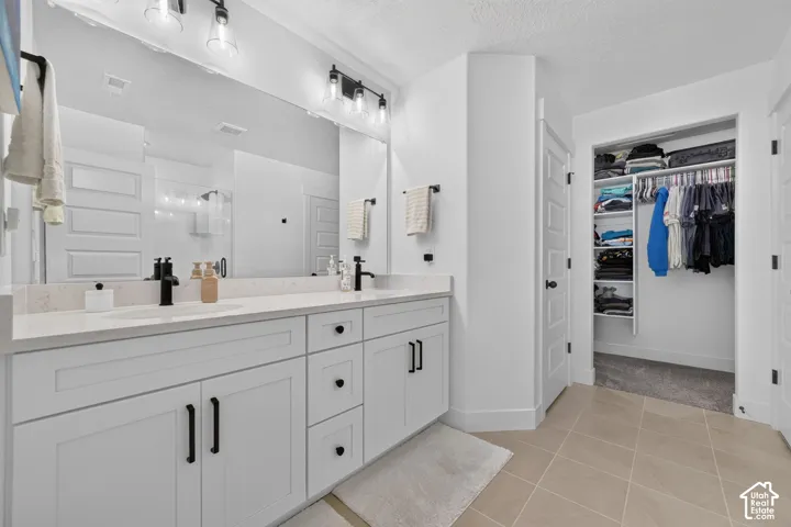 Primary bathroom featuring a double-sink vanity with white cabinetry, quartz countertops, and matte black hardware