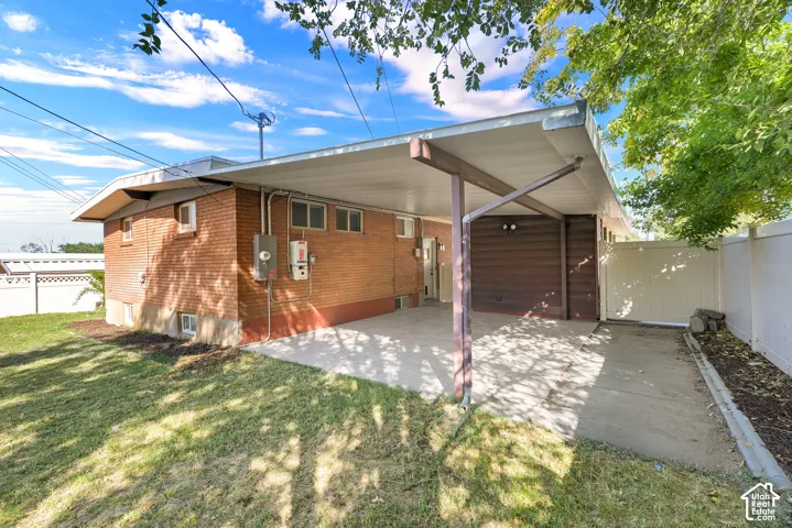 Covered patio area with concrete surfacing, brick exterior, wood-paneled siding, and a white privacy fence